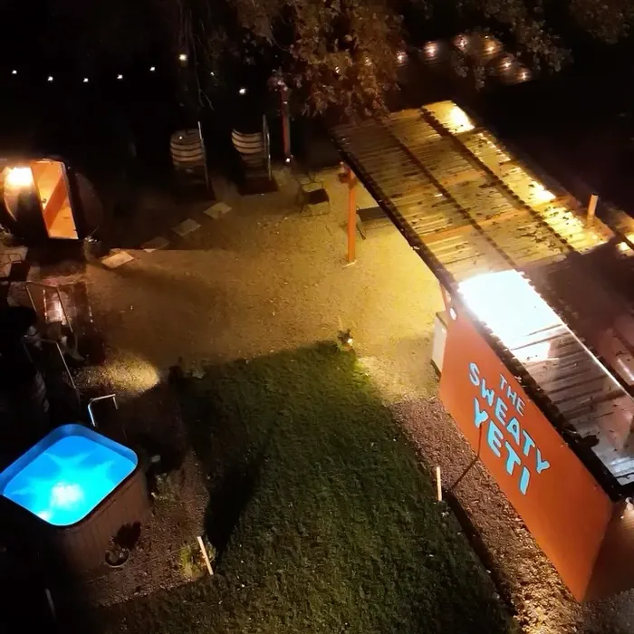 The yard from above at night, the hot tub glowing beside the lit cabin.
