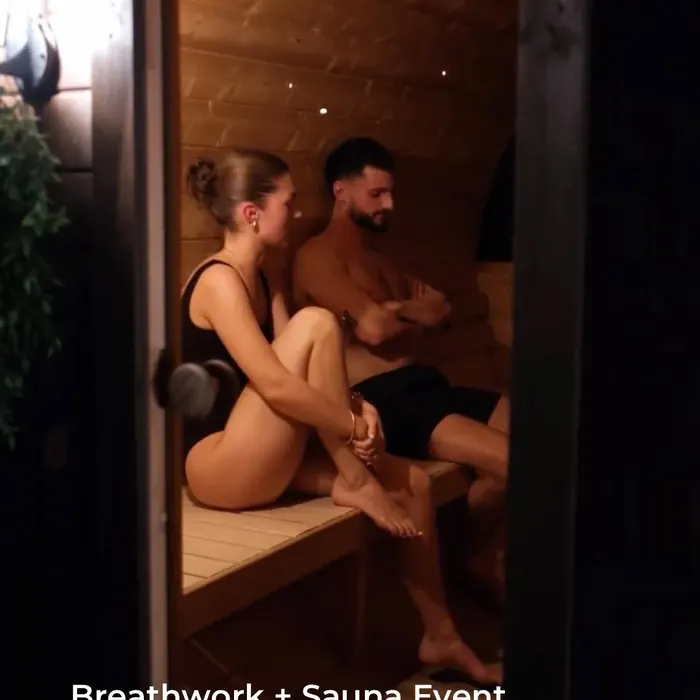 Two people resting on the bench inside the wood-fired sauna at a breathwork event.