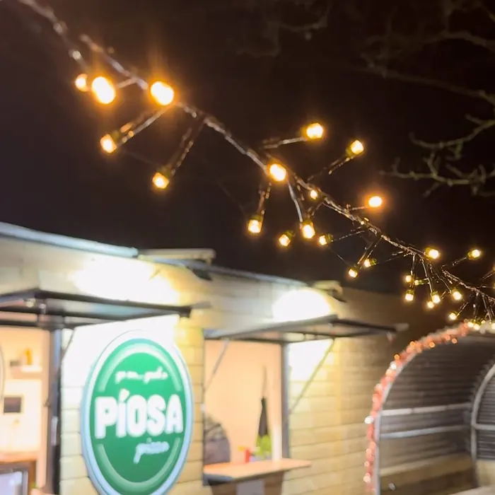 The Píosa pizza hatch lit up at night under strings of bulbs.