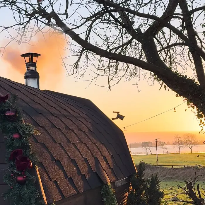 The sauna cabin at dawn with mist lying over the field behind it.